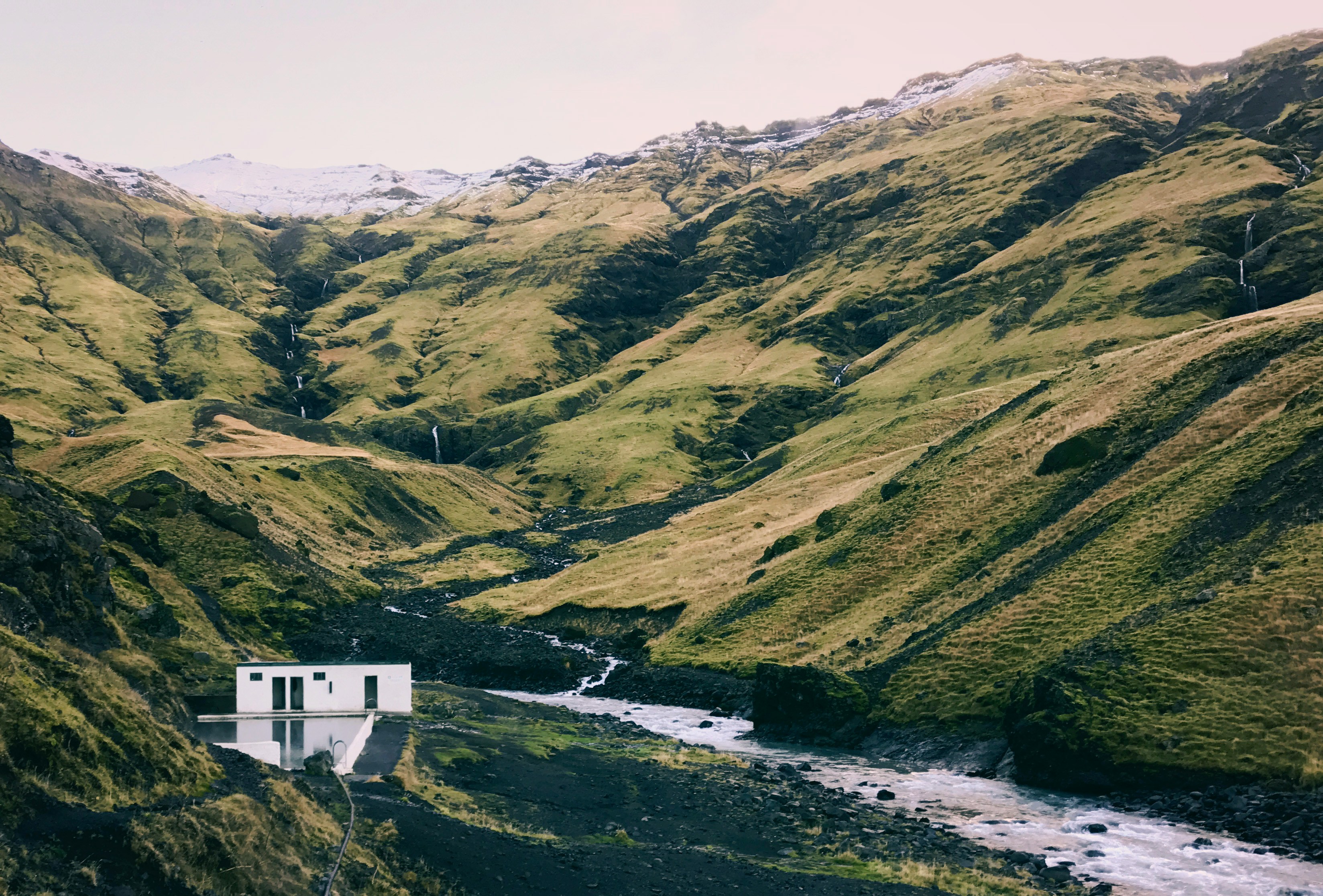 Seljavallalaug old swimming pool below mountains on the South Coast of Iceland