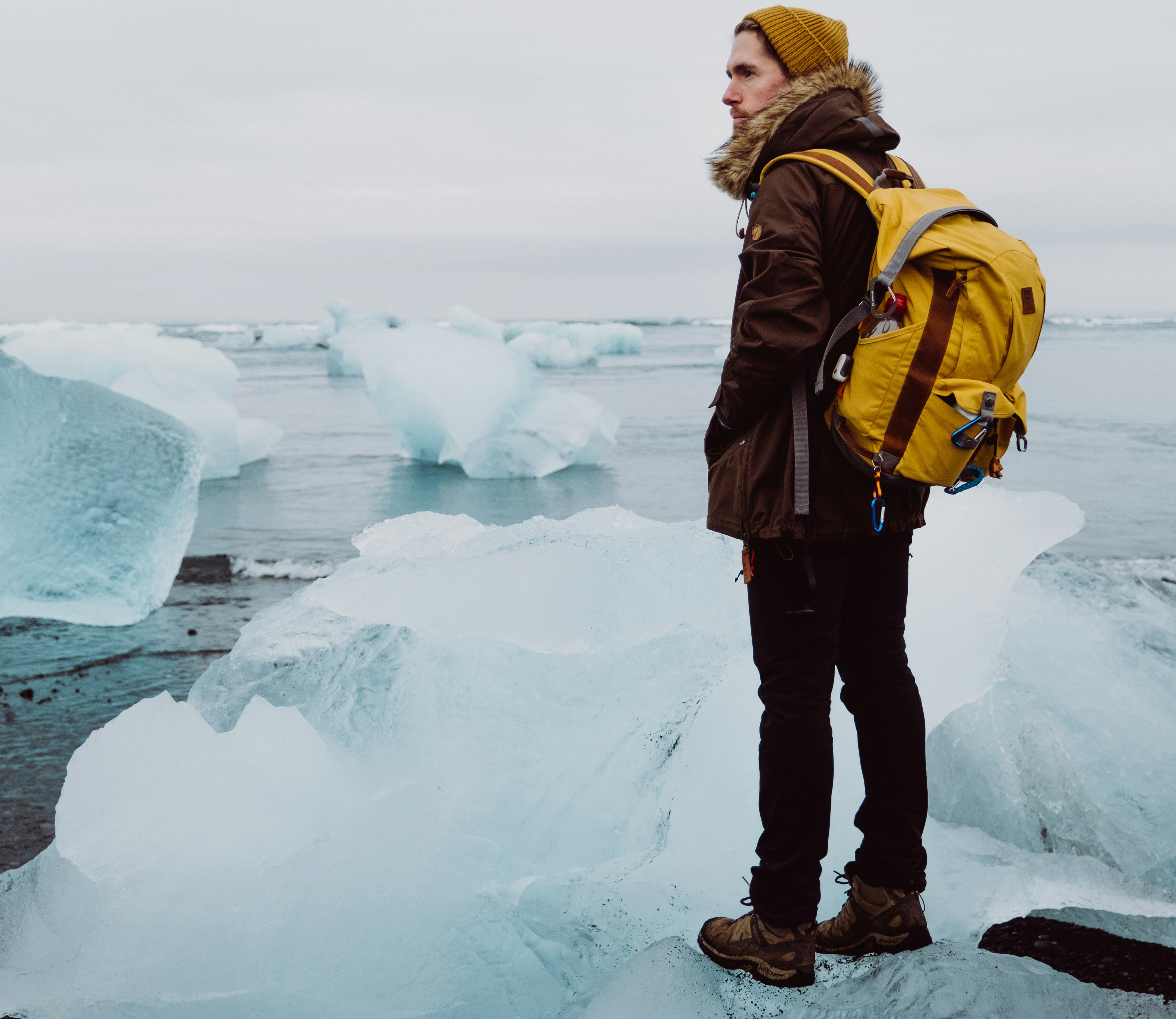 Traveller with yellow backpack at Diamond Beach, Iceland