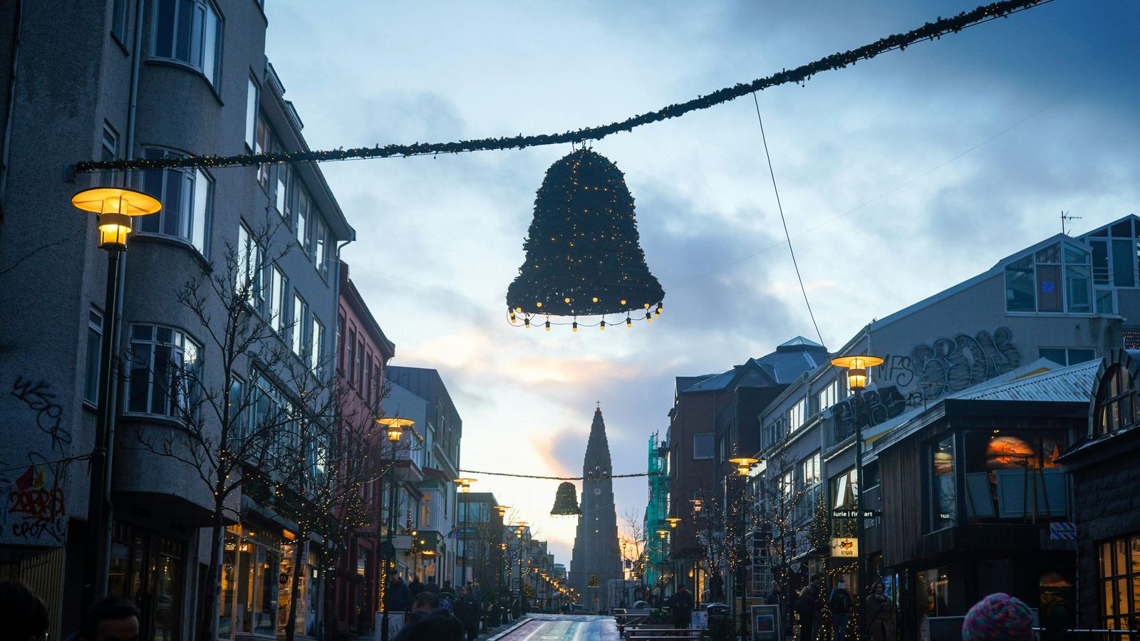 Christmas bell lights strung across Skólavörðustígur street in Reykjavík, with Hallgrímskirkja church at the top