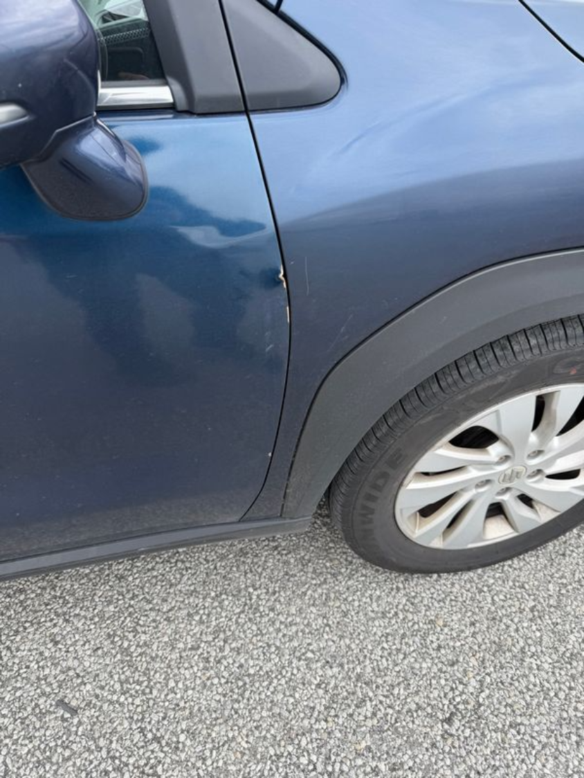 Close-up of a rental car stopped on loose gravel next to the road