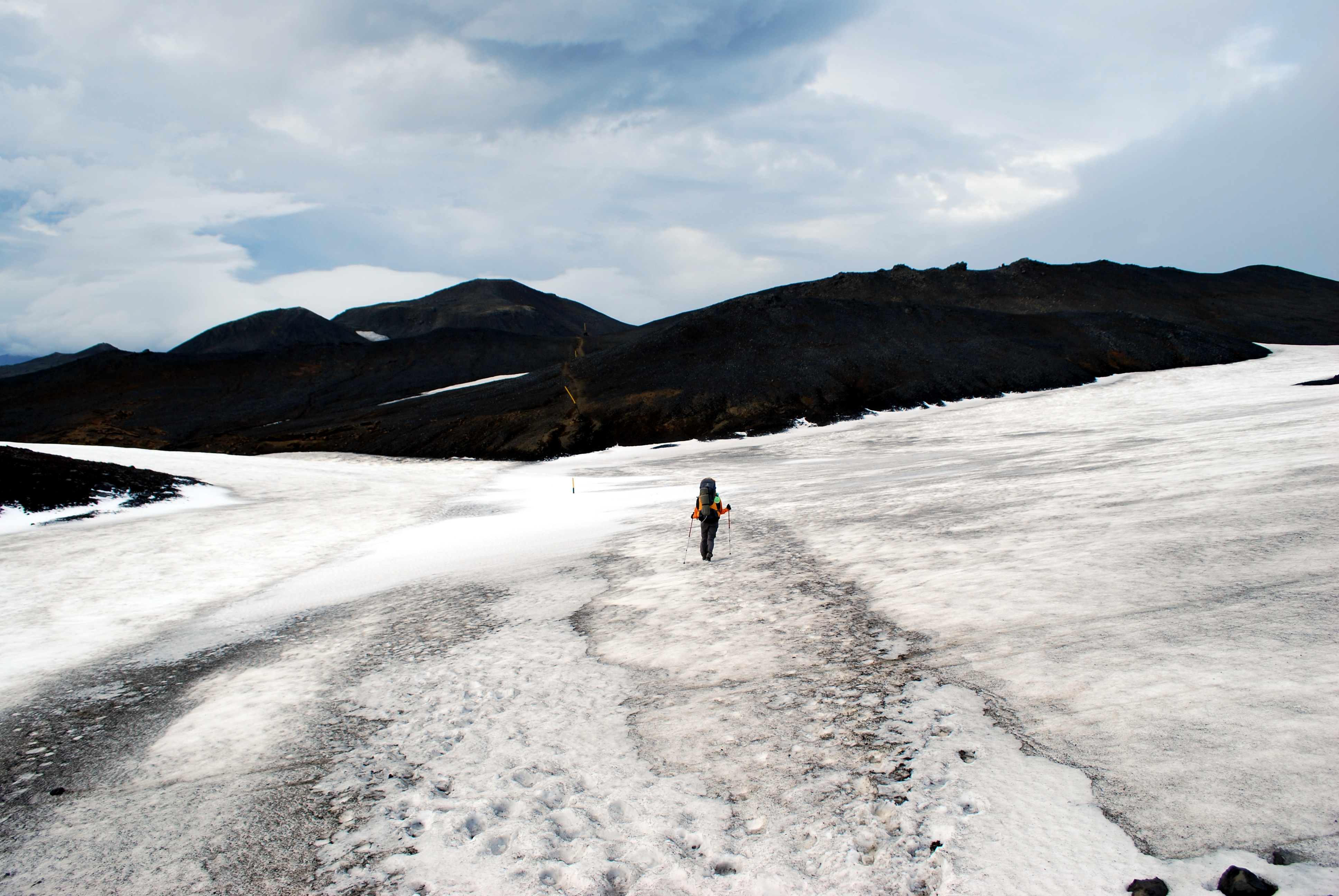Hiker crossing snow on the Fimmvörðuháls trail between glaciers