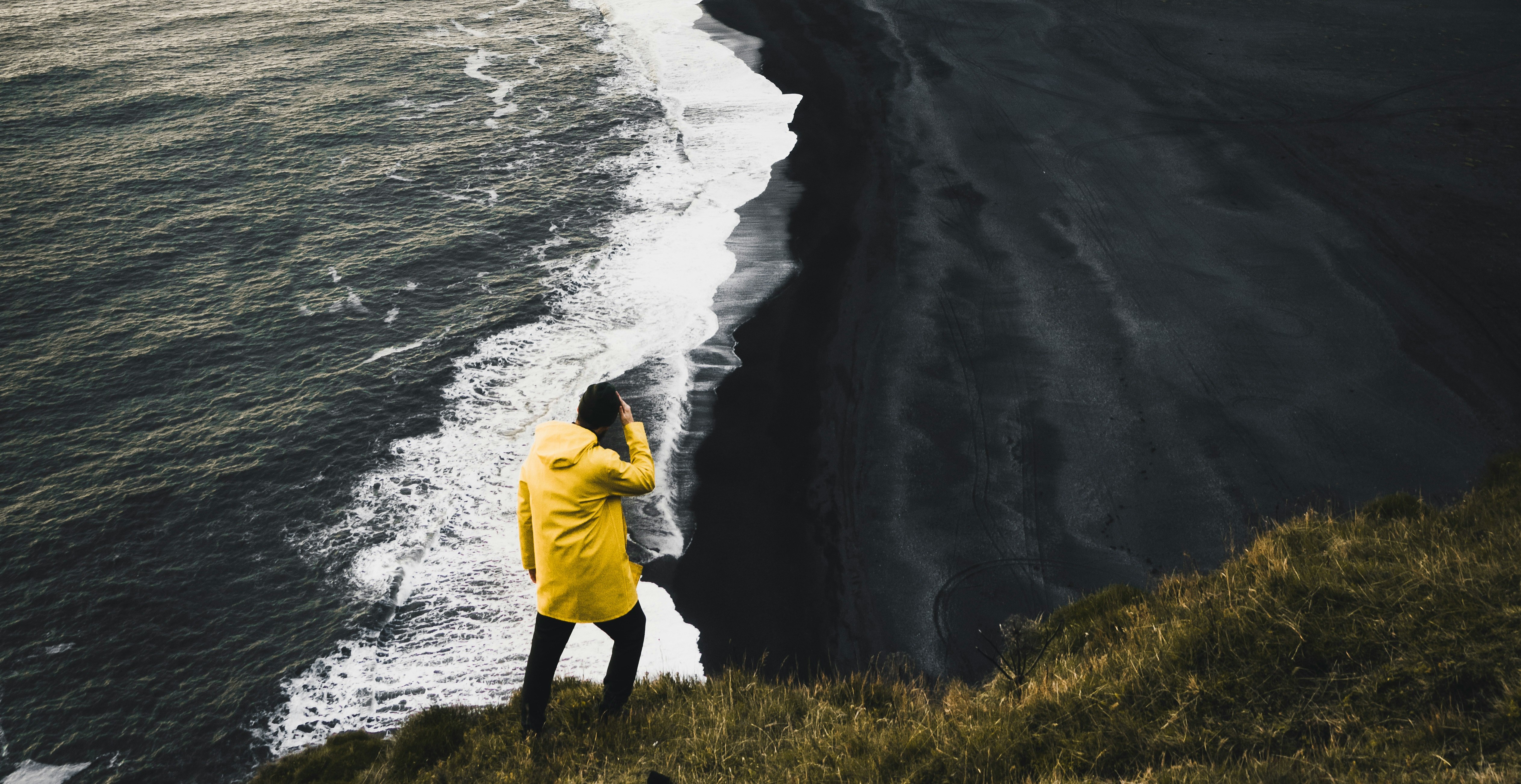 Traveller in yellow jacket on Iceland's dramatic coastline