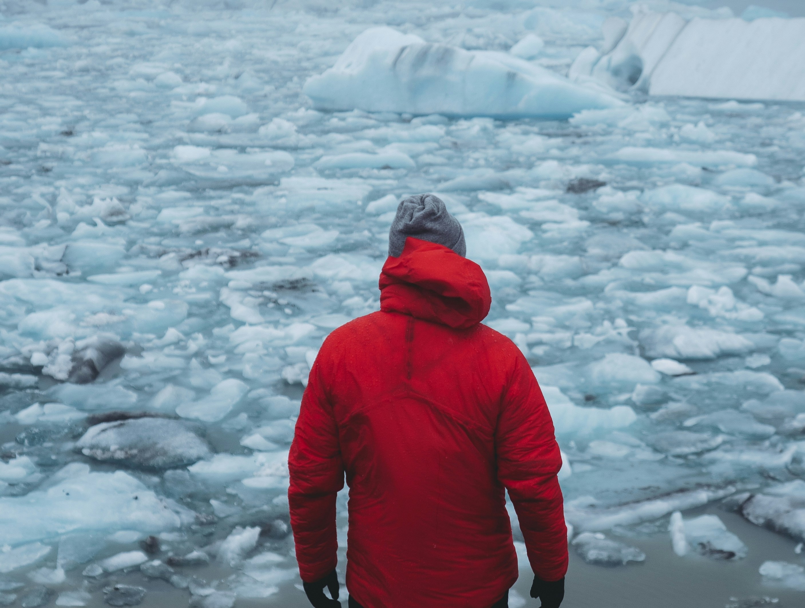 Traveller in red jacket at Jökulsárlón glacier lagoon in winter